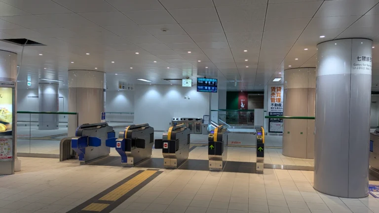 Fukuoka subway station ticket gates with Nanakuma Line signage, digital displays, and IC card readers at an empty entrance