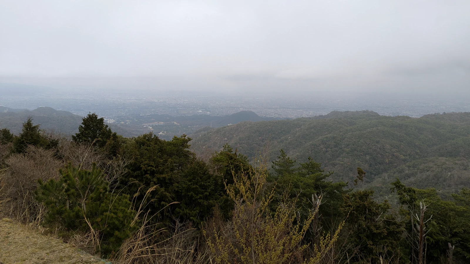 View from Mount Rokko near Kobe, Japan, with misty mountains and a hazy cityscape below.