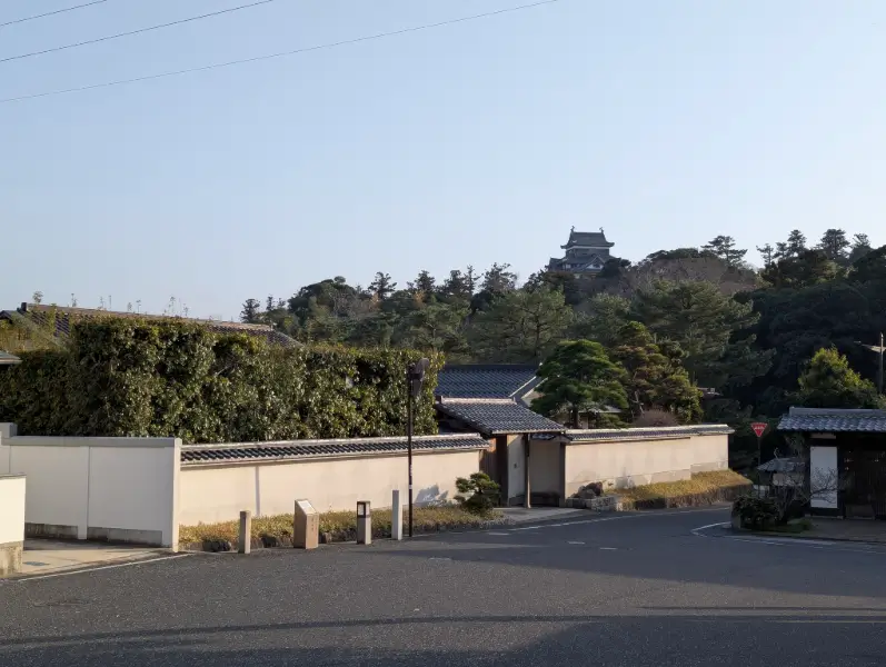 View of Matsue Castle rising above traditional samurai walls and rooftops in the historic district of Matsue in Chugoku, Japan.