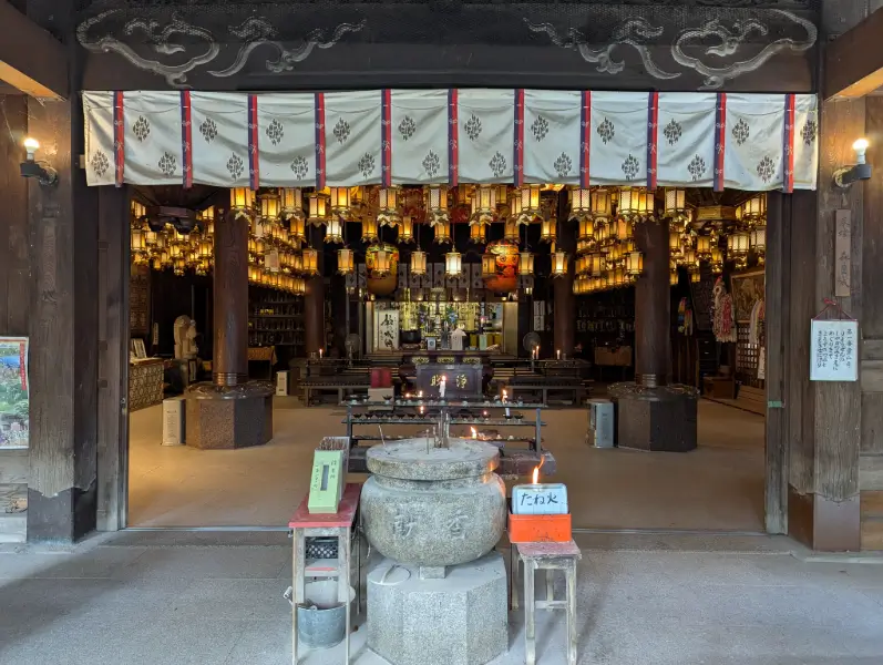 Lantern-lit interior of Ryozen-ji Temple with incense and altar, a sacred space marking the start of the Shikoku pilgrimage.