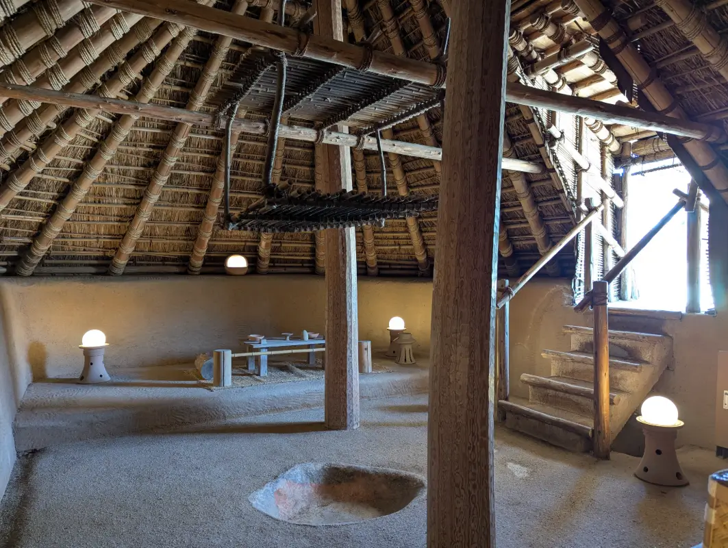 Inside a reconstructed Yayoi pit dwelling in Saga, showing wooden beams and a central hearth, echoes of Japan’s ancient village life.