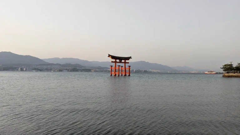 The iconic Otorii gate at Itsukushima Shrine standing tall in the Seto Inland Sea, captured at low tide. A sacred threshold marking the entrance to Miyajima, Japan.