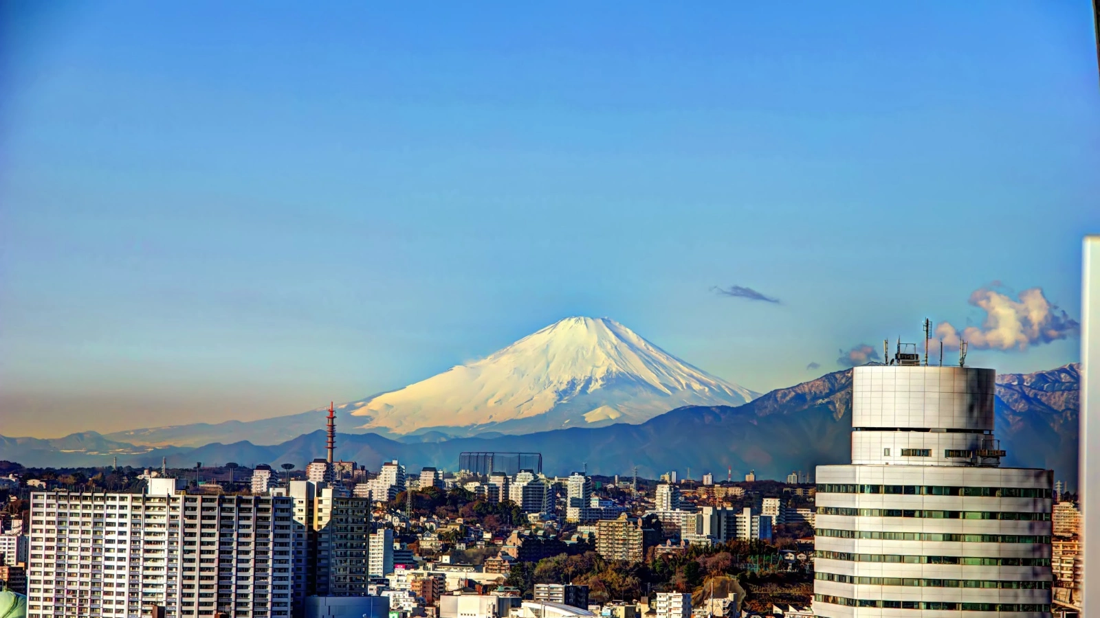 View of Mt. Fuji rising above the city skyline on a clear day, representing the harmony of tradition and modern Japan.