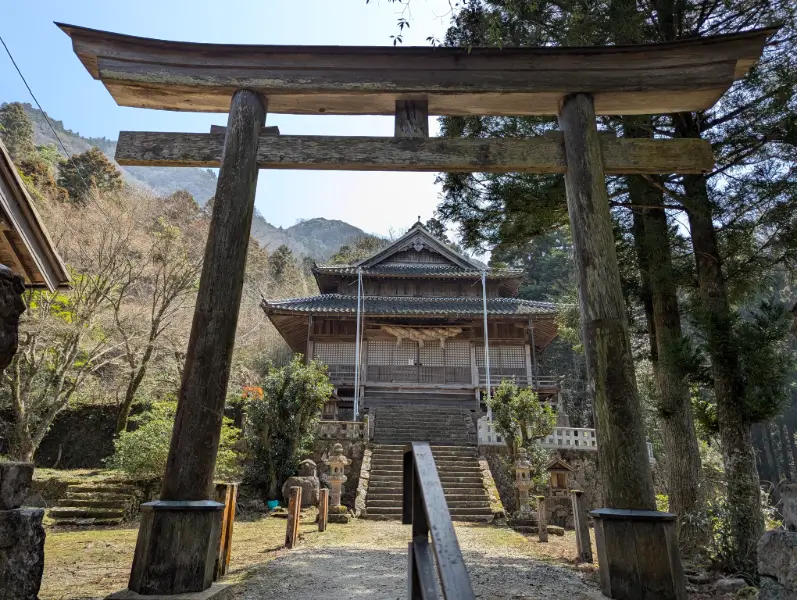Sahimeyama Shrine (佐毘賣山神社) in Iwami Ginzan, framed by a traditional torii gate and surrounded by tranquil forest paths.